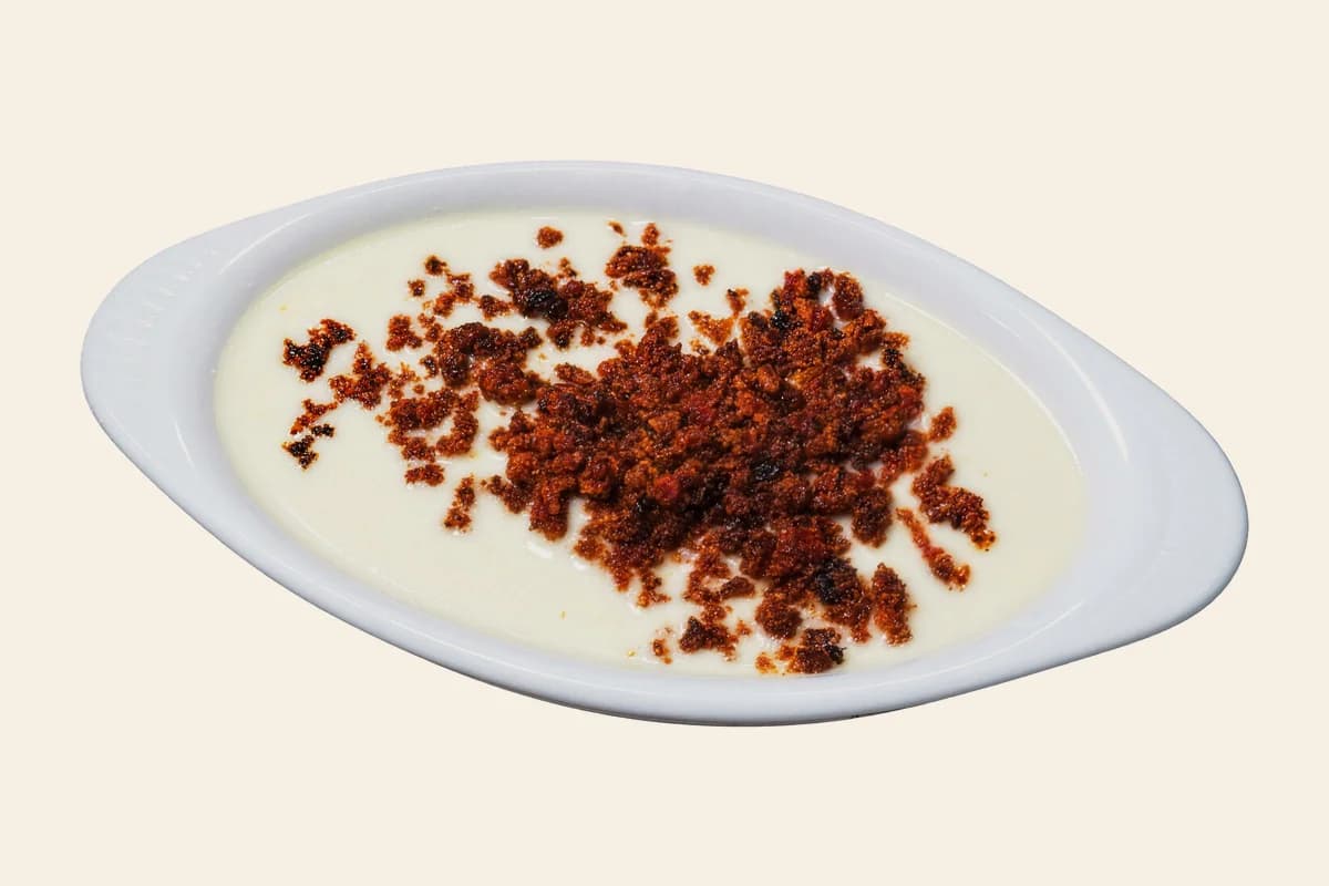 Chori queso: white cheese dip topped with crumbled chorizo in an oval dish