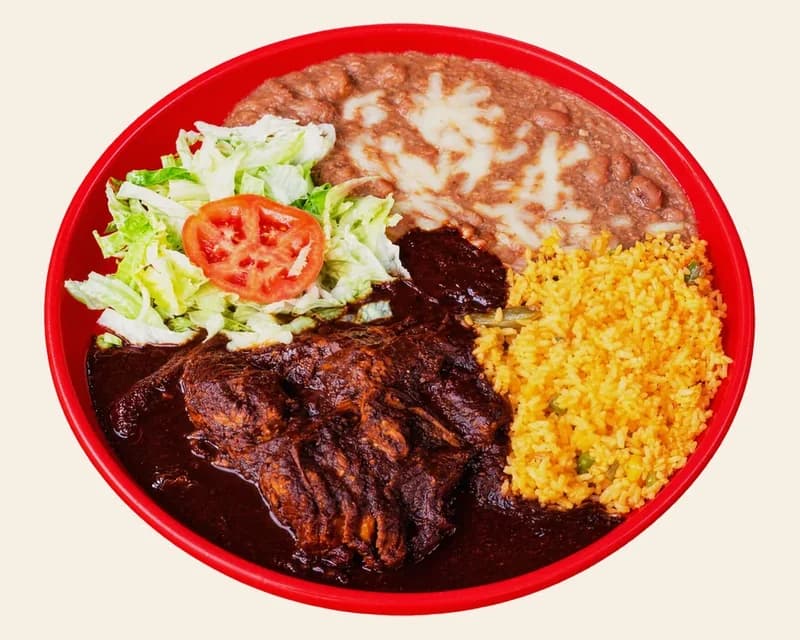 Mole mexicano: chicken in dark mole sauce with rice, refried beans, lettuce and tomato
