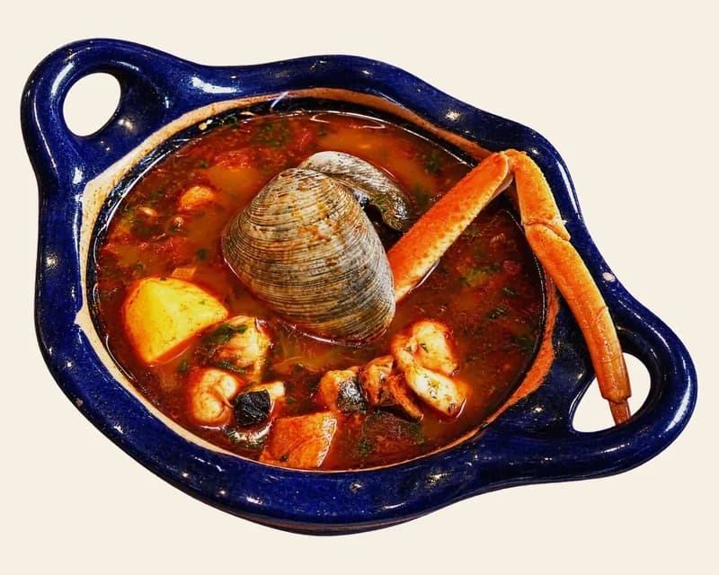 Siete mares seafood soup with crab leg, clam and shrimp in a blue clay bowl